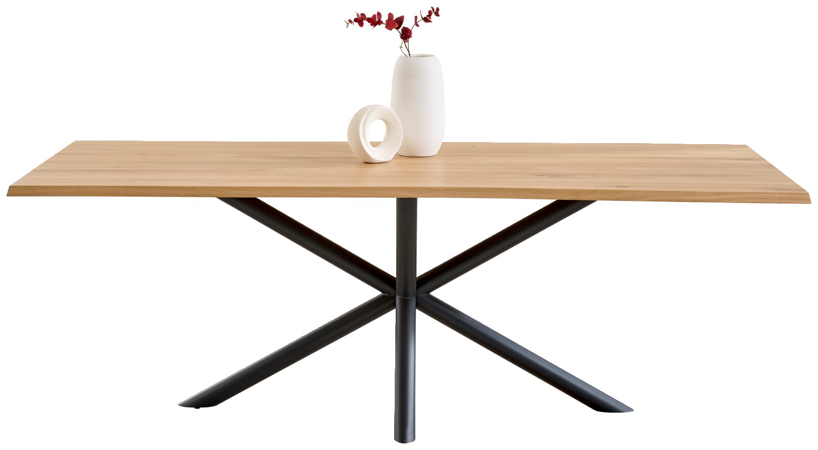 Rechteckiger Esstisch mit heller Holzplatte und schwarzem Metall-Kreuzgestell, frontal in leichter Seitenperspektive vor weißem Hintergrund; auf der Tischplatte stehen eine weiße Vase mit roten Zweigen und ein weißes Deko-Objekt.