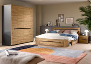 Modernes Schlafzimmer mit Holzbett inklusive Stauraum-Schublade, passendem Nachttisch und großem Kleiderschrank in Eiche-Optik, aufgenommen aus schräger Frontperspektive.