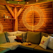Gemütliche Sitzecke mit LED-Kranz an der Holzwand, Perspektive von vorne.