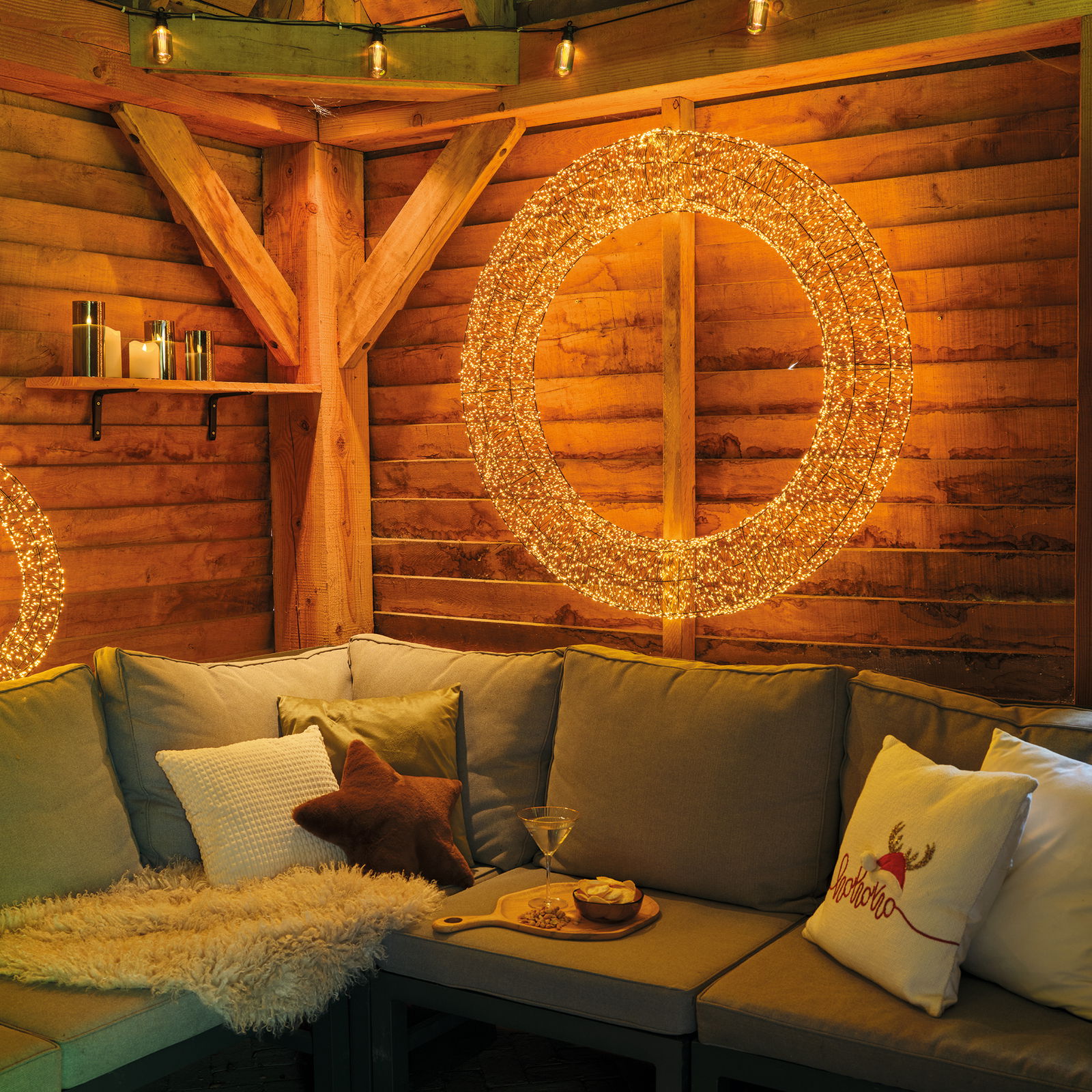 Gemütliche Sitzecke mit LED-Kranz an der Holzwand, Perspektive von vorne.