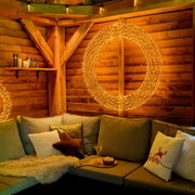 Gemütliche Sitzecke mit LED-Kranz an der Holzwand, Perspektive von vorne.