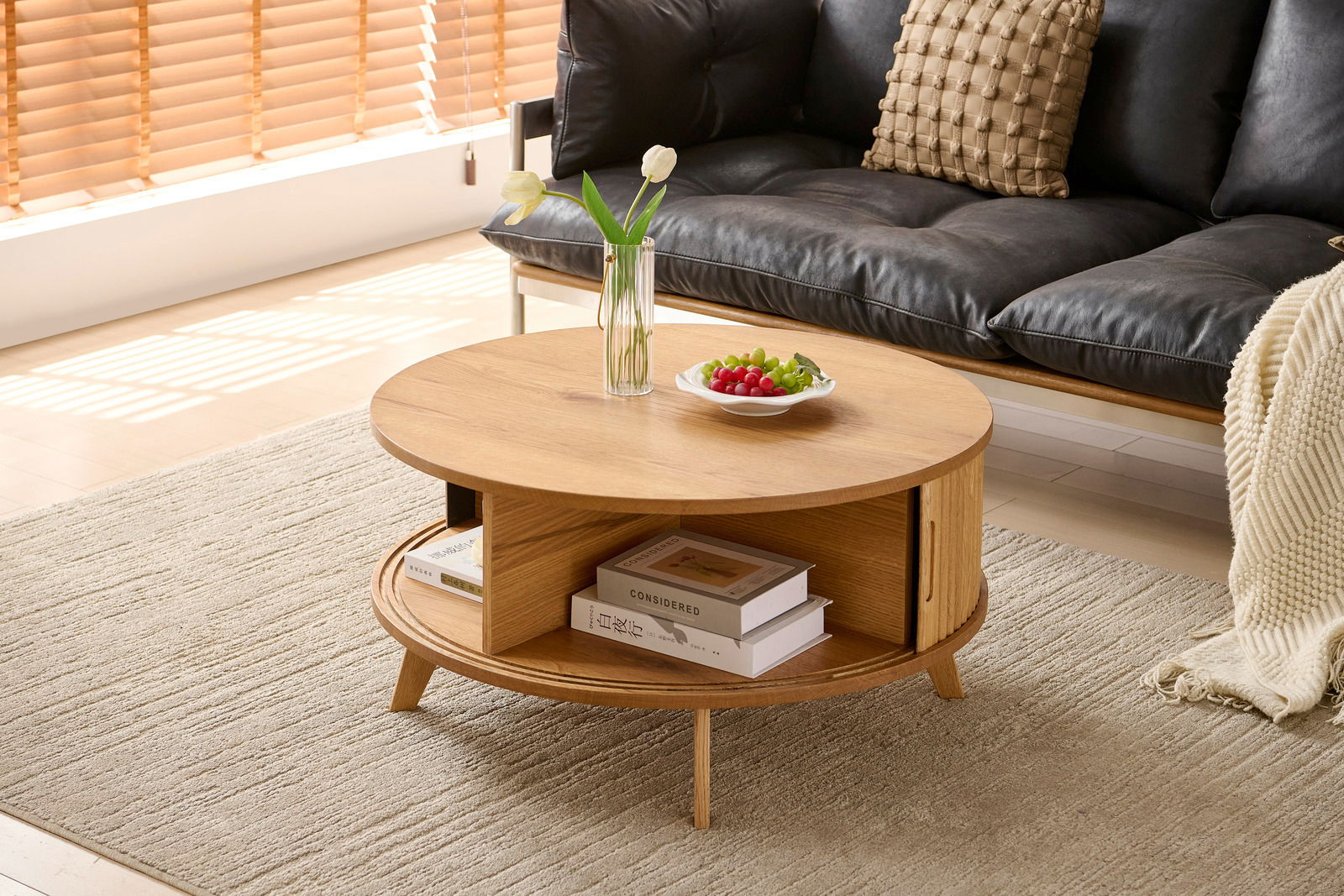 Runder Couchtisch aus Holz mit Stauraum, dekoriert mit einer Vase und Obstschale, seitliche Perspektive