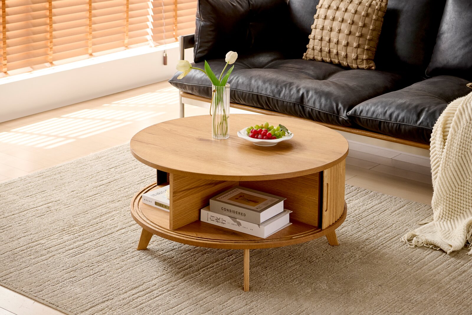 Runder Couchtisch aus Holz mit Stauraum, dekoriert mit einer Vase und Obstschale, seitliche Perspektive