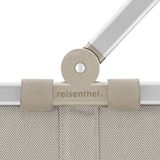 Nahaufnahme des oberen Teils eines Carrybags in Herringbone Sand mit sichtbarem Griff und dem Logo 'reisenthel'.