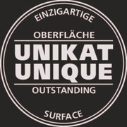 Rundes Siegel mit der Aufschrift 'Einzigartige Oberfläche, Unikat, Outstanding, Unique, Surface' in schwarzer Schrift auf weißem Hintergrund, Draufsicht.