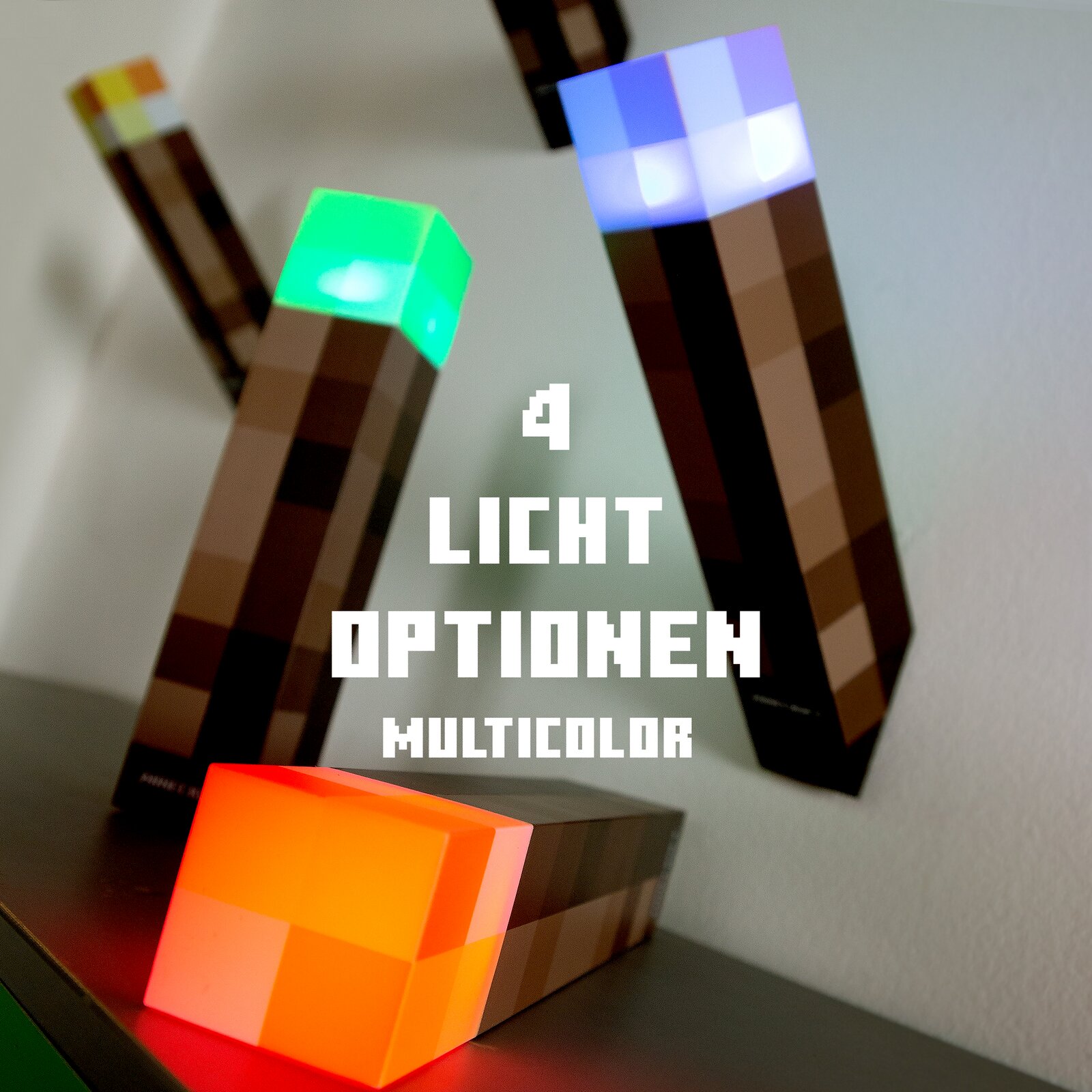 Minecraft-inspirierte LED-Fackeln mit pixeligem Design und leuchtenden Köpfen in Grün, Blau und Orange, schräg aus der Vorderansicht auf einem Regal fotografiert; Text im Bild: „4 Licht Optionen Multicolor“.