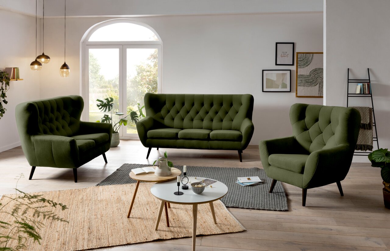 Grünes Sofa-Set bestehend aus einem 3-Sitzer, einem 2-Sitzer und einem Sessel in einem modernen Wohnzimmer mit Holzboden und großen Fenstern, seitliche Perspektive.