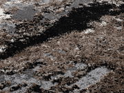 Nahaufnahme eines Designer-Teppichs mit abstraktem Muster in Braun-, Grau- und Schwarztönen, aus der Vogelperspektive fotografiert.