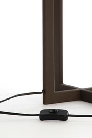 Nahaufnahme eines Lampenfußes mit rechteckigem Metallrahmen und einem schwarzen Kabel mit Schalter, seitliche Perspektive.