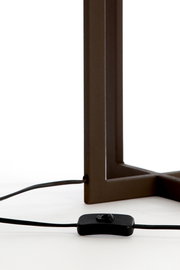 Nahaufnahme eines Lampenfußes mit rechteckigem Metallrahmen und einem schwarzen Kabel mit Schalter, seitliche Perspektive.