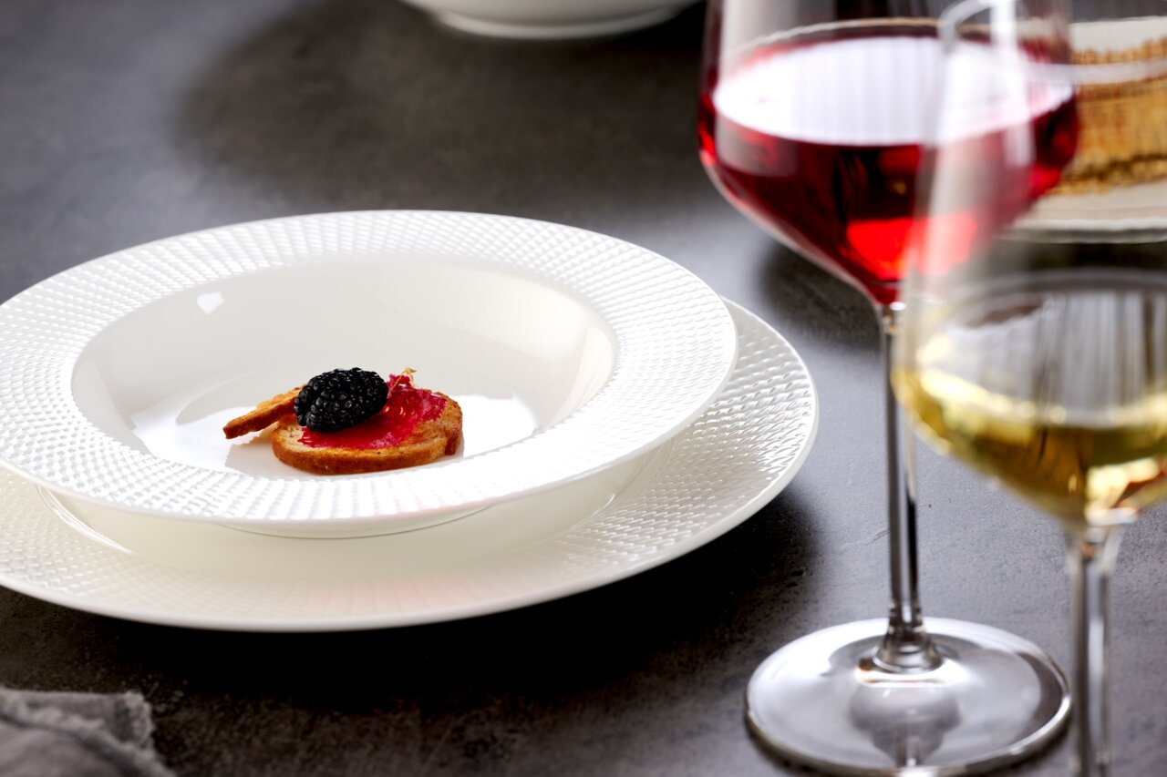 Suppenteller 27cm mit feiner Struktur, von oben fotografiert, serviert mit einer kleinen Vorspeise und umgeben von Weingläsern.