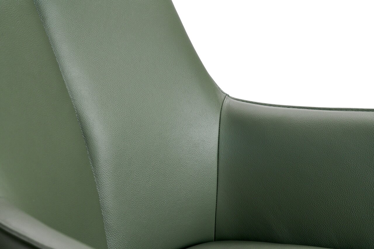 Nahaufnahme eines grünen Armlehnstuhls aus Leder, Fokus auf die Rückenlehne und Armlehne, seitliche Perspektive