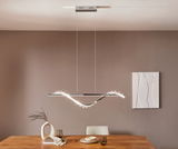 Moderne LED-Hängeleuchte in geschwungenem Design über einem Esstisch, seitliche Perspektive.
