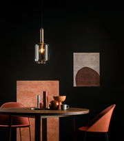 Moderne Pendelleuchte JOANET in einem stilvollen Esszimmer, mit warmem Licht und eleganter Glas- und Metallkombination, aus der Perspektive eines Betrachters auf Augenhöhe.
