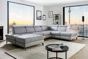Graue Rundecke (L) in modernem Wohnzimmer mit Blick auf die Stadt, von vorne links gesehen.
