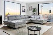 Graue Rundecke (L) in modernem Wohnzimmer mit Blick auf die Stadt, von vorne links gesehen.