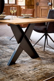 Moderner Esstisch mit X-förmigem Metallgestell und Holzplatte, seitliche Perspektive