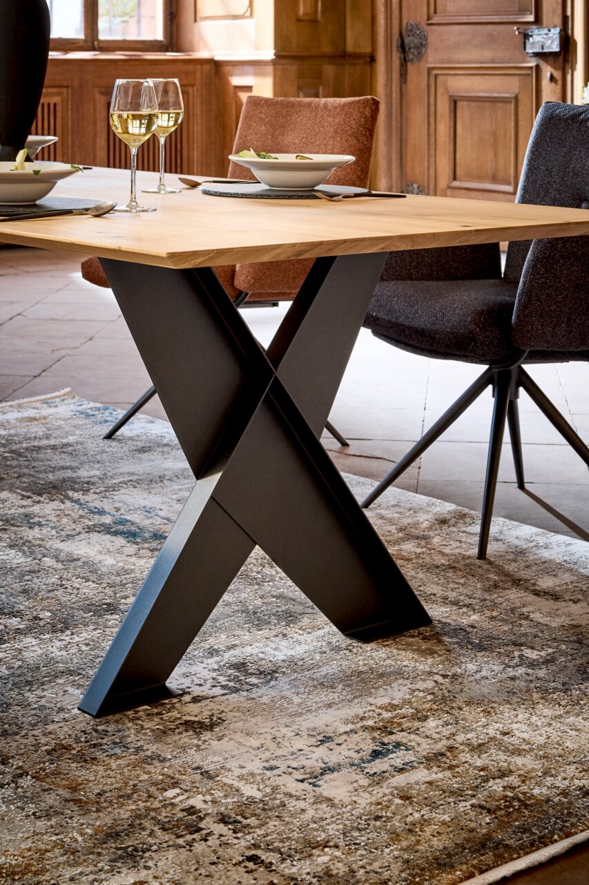 Moderner Esstisch mit X-förmigem Metallgestell und Holzplatte, seitliche Perspektive