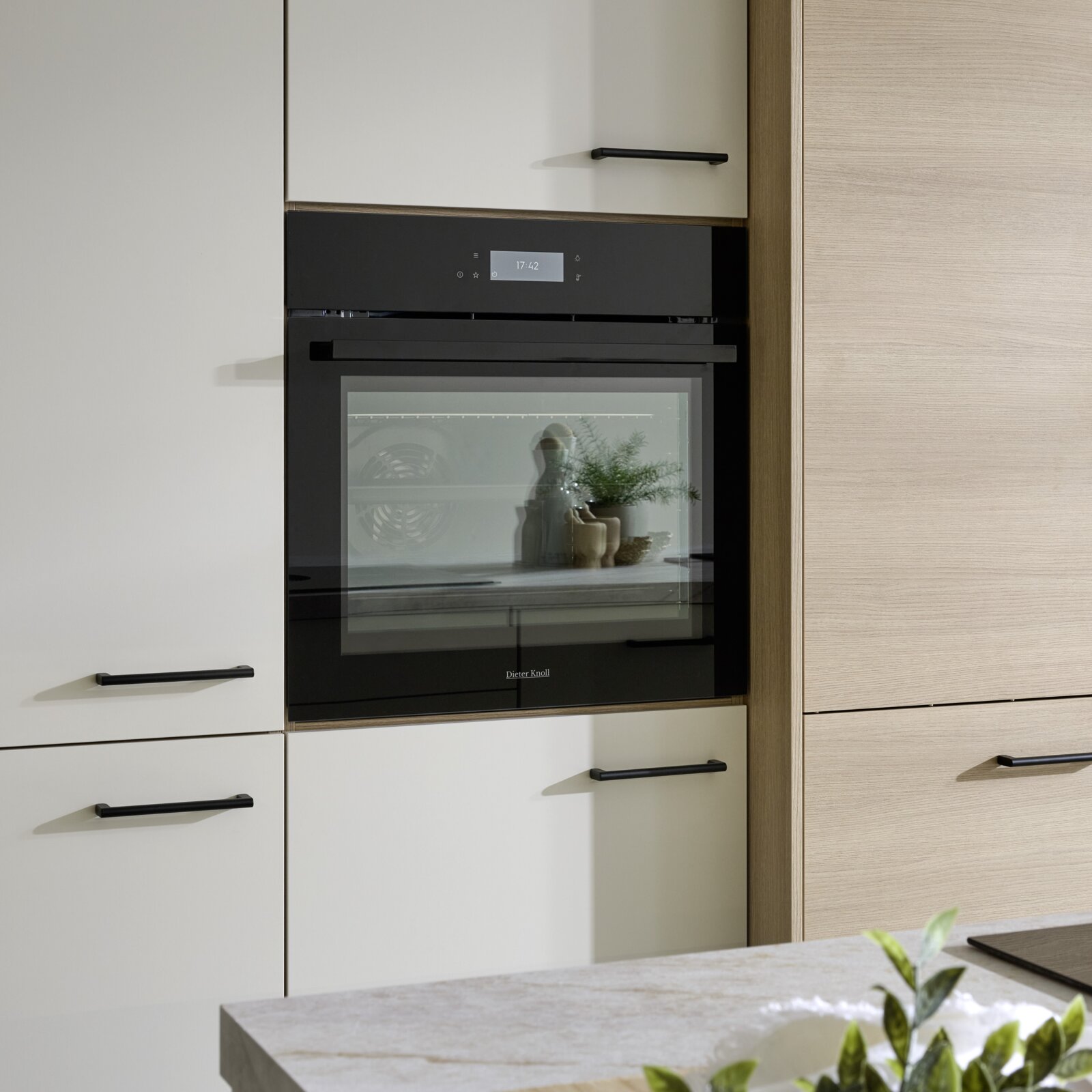 Ingebouwde zwarte glazen oven met digitaal display in moderne keukenwand, frontaal aanzicht op ooghoogte.