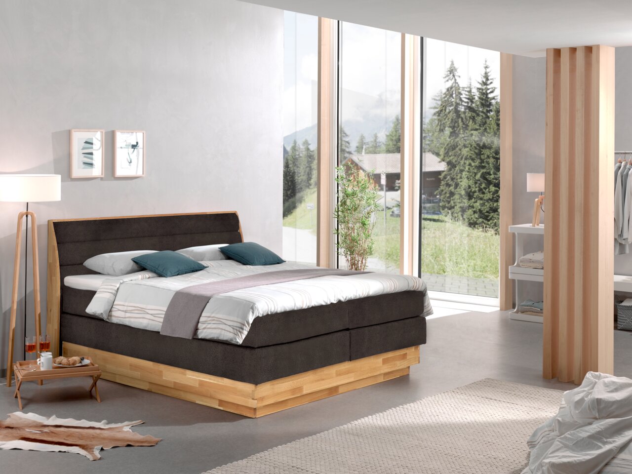 Z2 Boxspringbett MARISSA Modernes Boxspringbett in einem hellen Schlafzimmer mit großen Fenstern und Blick auf die Natur, seitliche Perspektive.