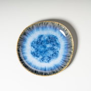Runder, blau glasierter Keramik-Teller mit reaktivem Farbverlauf und braunem Rand, fotografiert in Draufsicht von oben auf weißem Hintergrund.