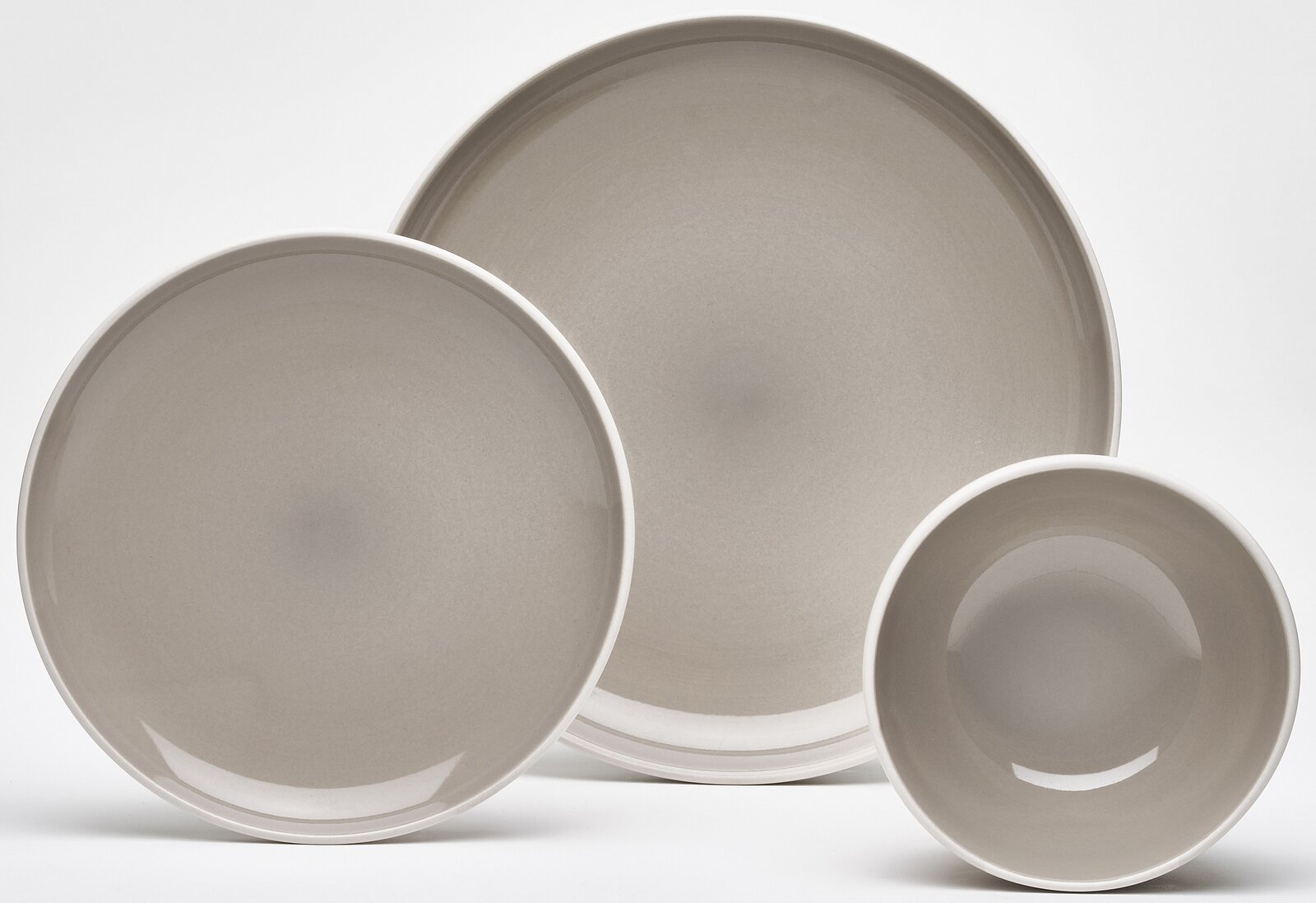 Dreiteiliges Kombiservice in neutralem Grau, bestehend aus zwei Tellern und einer Schüssel, aus der Vogelperspektive fotografiert.