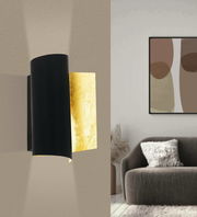 Moderne Wanleuchte FALICETTO in Schwarz und Gold, seitliche Perspektive, an einer beigen Wand montiert, mit Lichtstrahlen nach oben und unten.