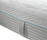 Nahaufnahme einer Gel-Kaltschaummatratze mit gestepptem Muster und blauer Zierleiste, seitliche Perspektive.