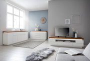 Moderne Wohnzimmermöbel in heller Umgebung mit Sideboard, TV-Lowboard und Kommode aus weißem Holz mit dunkler Holzplatte, seitliche Perspektive.