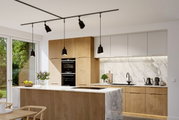 Moderne Küche mit Holz- und Marmorelementen, zentraler Kücheninsel und hängenden schwarzen Lampen, Blick von der Seite.