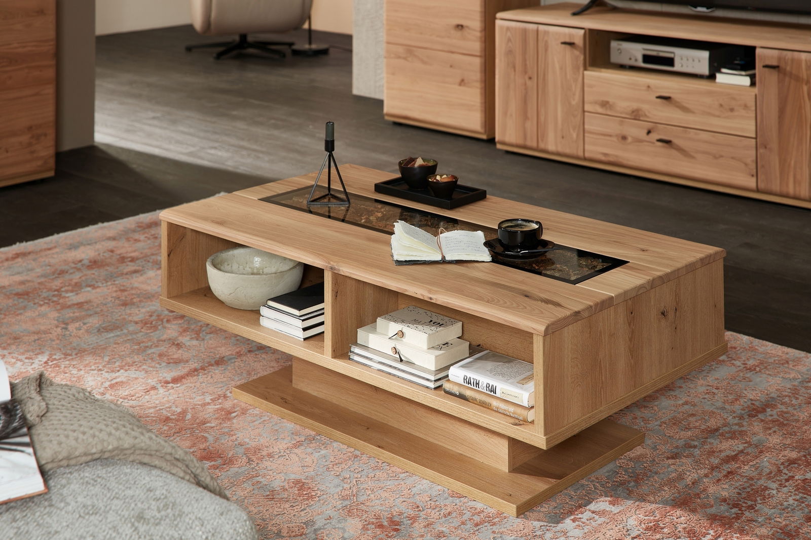 Cantus Couchtisch CALMERA Moderner Couchtisch aus Holz mit offenen Fächern, dekoriert mit Büchern und einer Tasse Kaffee, in einem gemütlichen Wohnzimmer. Perspektive von schräg vorne.