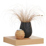 Wandboard aus Holz mit schwarzer Vase und getrockneten Gräsern, daneben ein Teelichthalter aus Holz, seitliche Perspektive