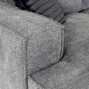Nahaufnahme einer grauen Sofaecke mit strukturiertem Stoffbezug und einem dekorativen Kissen, Perspektive von oben.