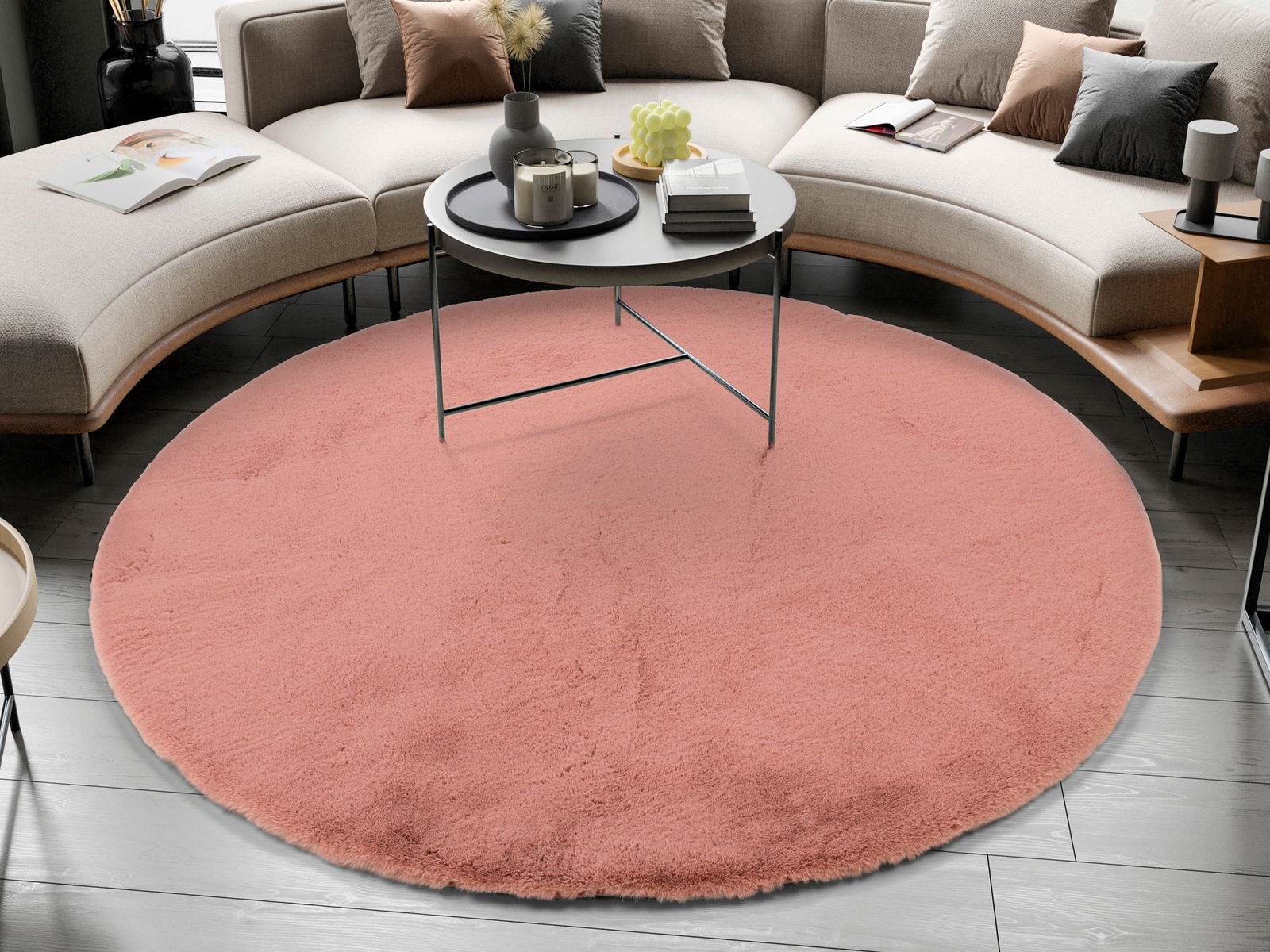 Runder, rosafarbener Fellteppich in einem modernen Wohnzimmer, von oben betrachtet, unter einem runden Couchtisch platziert.