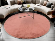 Runder, rosafarbener Fellteppich in einem modernen Wohnzimmer, von oben betrachtet, unter einem runden Couchtisch platziert.
