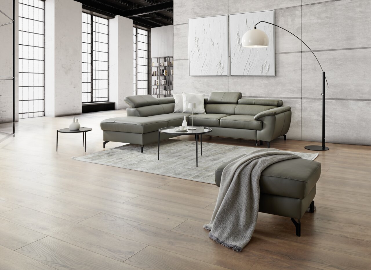 Moderne Eckgarnitur in einem hellen, stilvollen Wohnzimmer mit großen Fenstern und Holzboden, seitliche Perspektive.