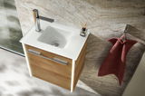 Waschbecken mit Holzunterschrank und moderner Armatur, von oben fotografiert, neben einem roten Handtuch an der Wand.