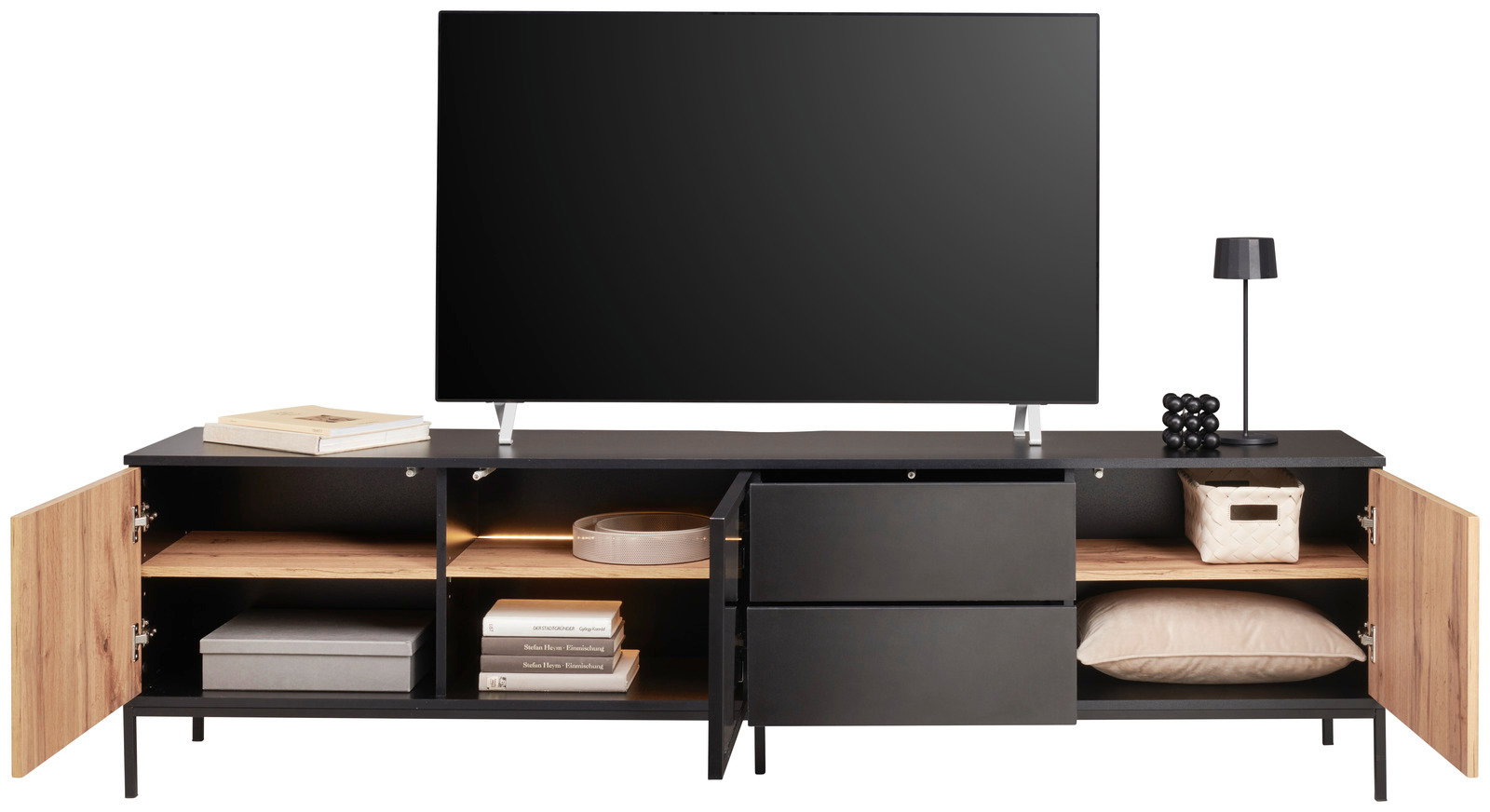 Frontansicht eines XL-TV-Lowboards mit offenen Schränken und Schubladen, dekoriert mit Büchern, einer Lampe und einem Fernseher.