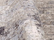 Nahaufnahme eines Designer Teppichs mit abstraktem Muster in Grau- und Beigetönen, seitliche Perspektive