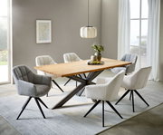 Moderner Esstisch mit heller Holzplatte und schwarzem X-Gestell, umgeben von gepolsterten Stühlen in Grau und Beige in einem hellen Esszimmer; Perspektive: leicht erhöhte Frontansicht schräg von links.