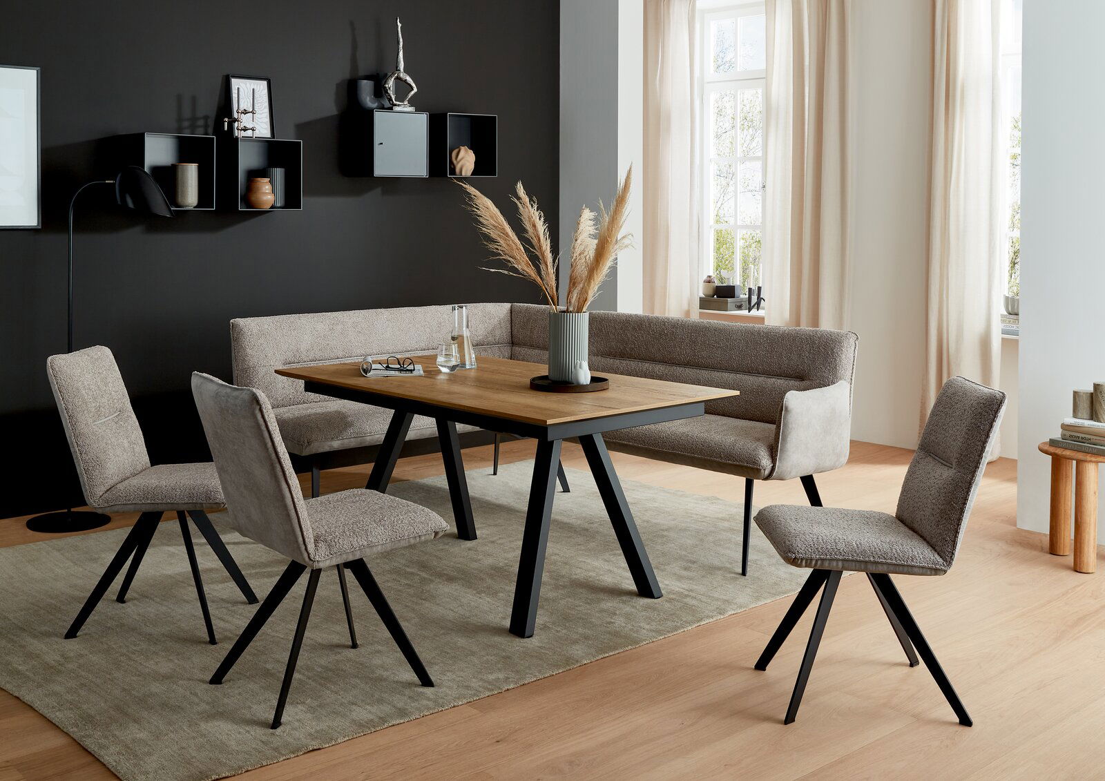 Moderner Esstisch mit Holzplatte und schwarzen Metallbeinen, umgeben von gepolsterten Stühlen und einer Eckbank in einem stilvoll eingerichteten Esszimmer. Perspektive: Frontalansicht.