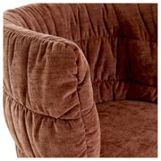 Close-up van een bruine fauteuil met zachte bekleding, gezien vanaf de zijkant