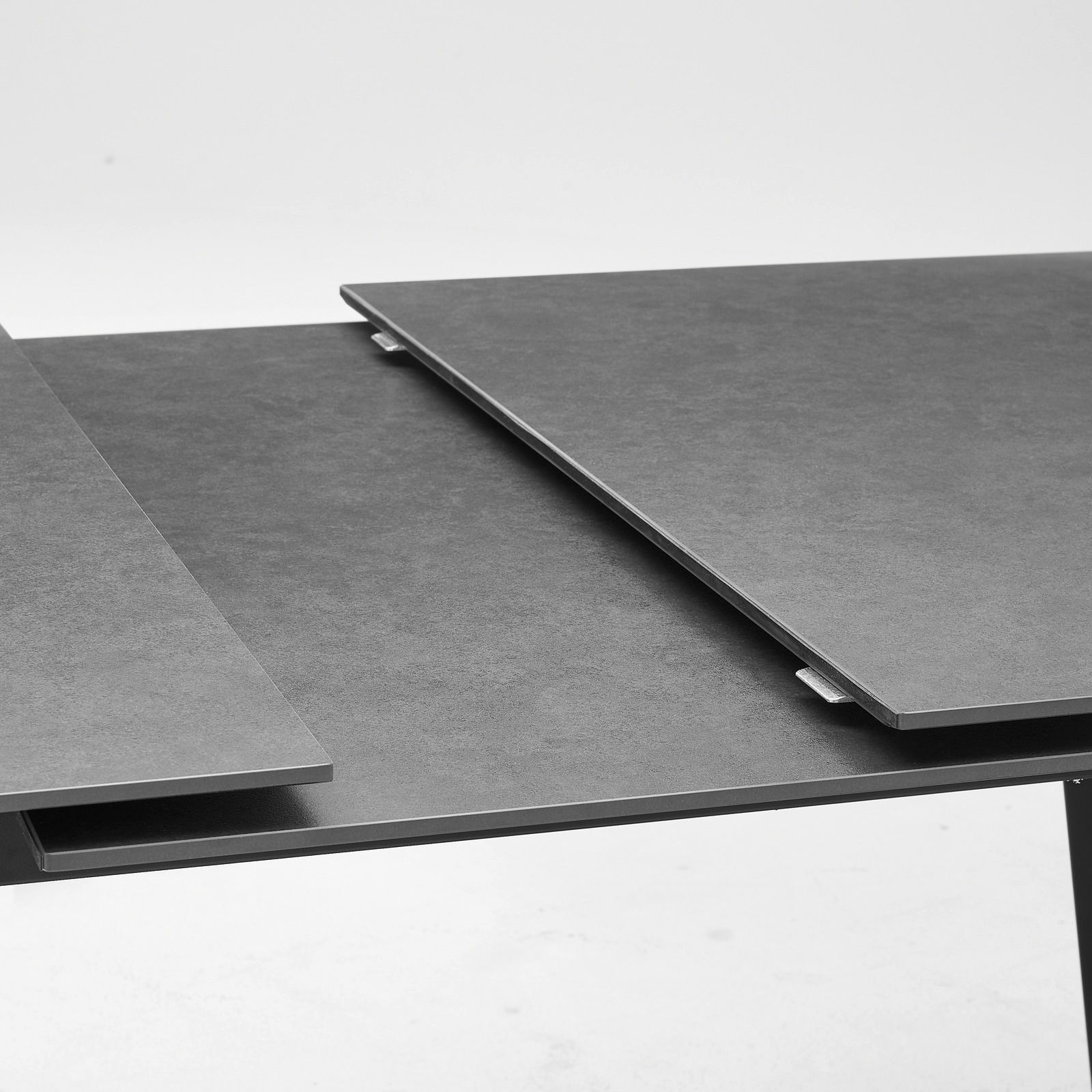 Nahaufnahme eines modernen, ausziehbaren Esstisches mit dunkler Oberfläche.