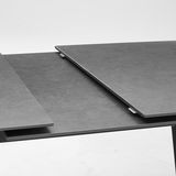 Nahaufnahme eines modernen, ausziehbaren Esstisches mit dunkler Oberfläche.