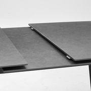 Nahaufnahme eines modernen, ausziehbaren Esstisches mit dunkler Oberfläche.