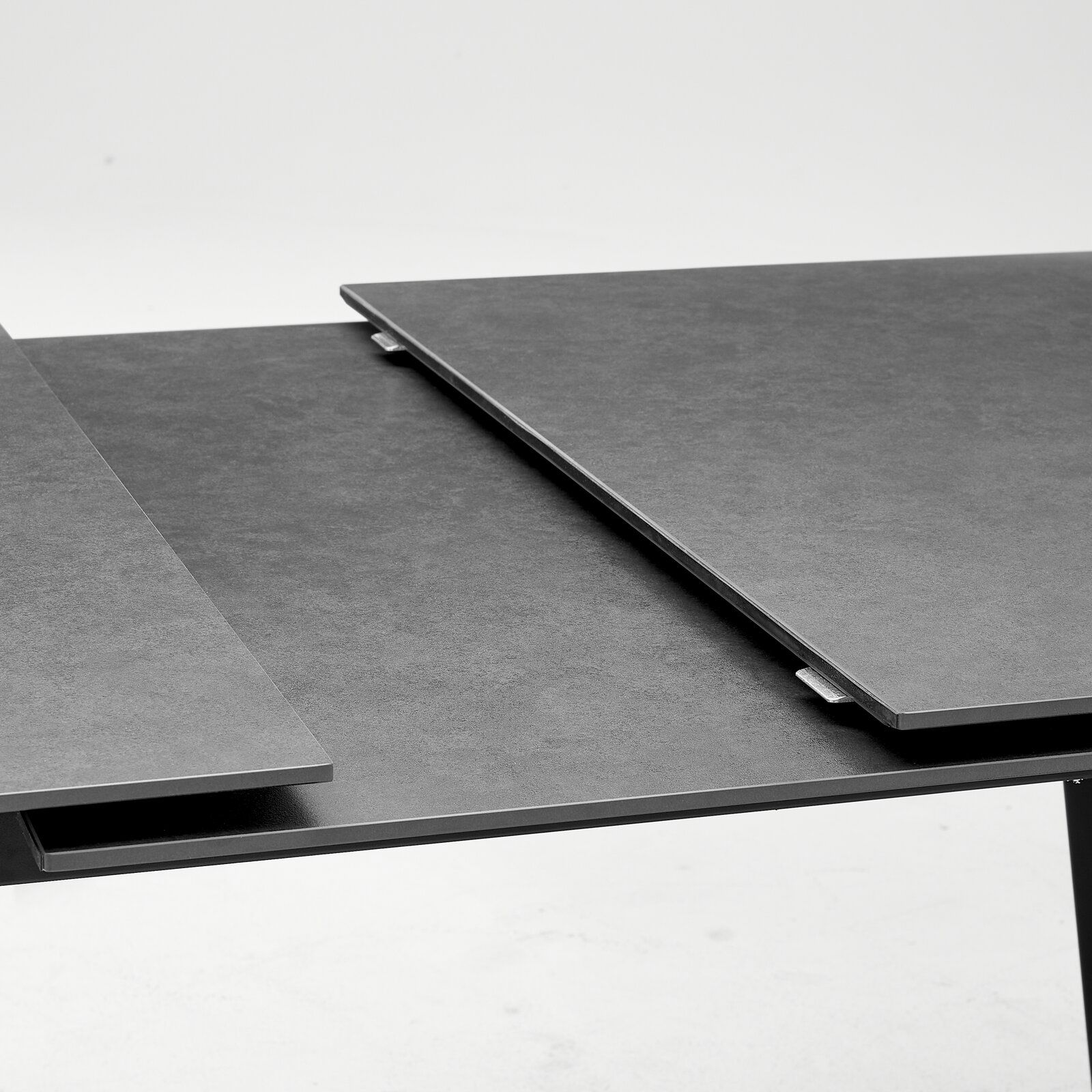 Nahaufnahme eines modernen, ausziehbaren Esstisches mit dunkler Oberfläche.