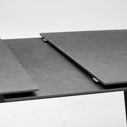 Nahaufnahme eines modernen, ausziehbaren Esstisches mit dunkler Oberfläche.