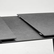 Nahaufnahme eines modernen, ausziehbaren Esstisches mit dunkler Oberfläche.