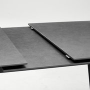 Close-up van een moderne, uitschuifbare eettafel met een donker oppervlak.