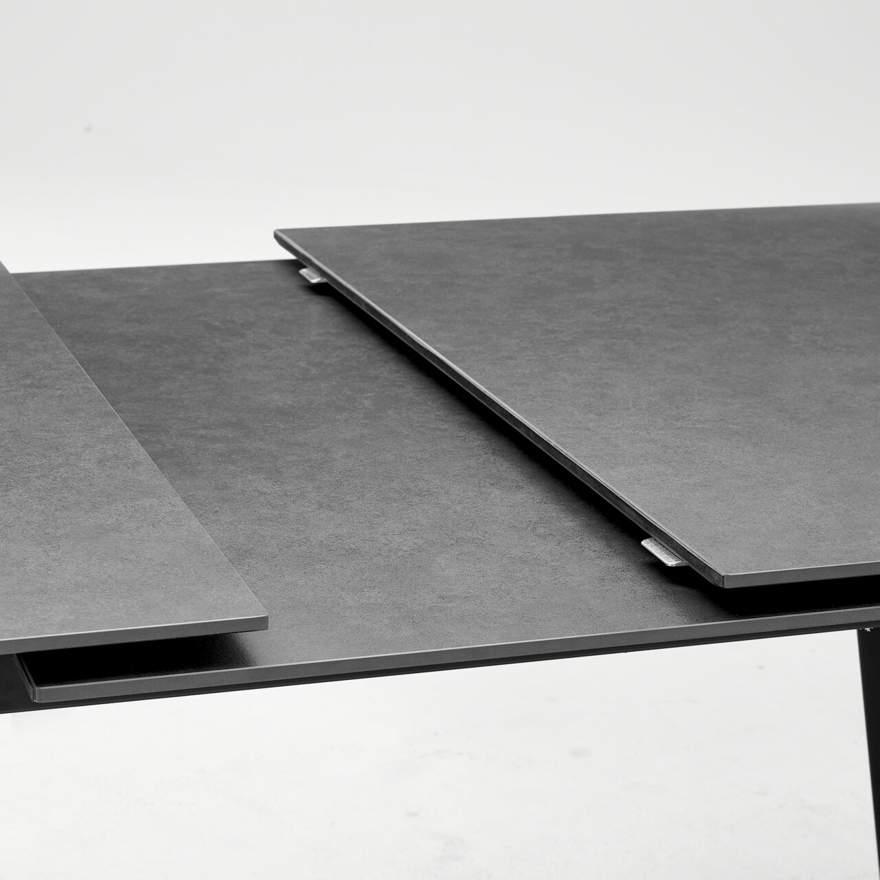 Close-up van een moderne, uitschuifbare eettafel met een donker oppervlak.